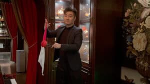 Magician holding a pink and white fantasy rose in a magic show setting.