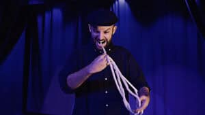 Magician performing the Mouth Coil Pro trick with a coil in his mouth on stage.