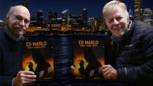 Two men holding Ed Marlo 40 Years Later book with NYC skyline background.