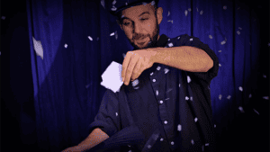 Magician performing SnowStorm Pro illusion with falling confetti on stage.