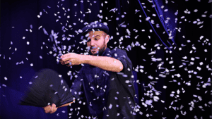 Performer creates snowstorm illusion with confetti during magic show.