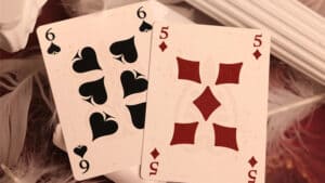 Close-up of playing cards featuring the 6 and 5 of Spades and 5 of Diamonds.