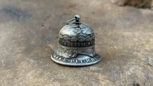 Vintage coin-shaped bell used in magic tricks, crafted with detailed engravings.