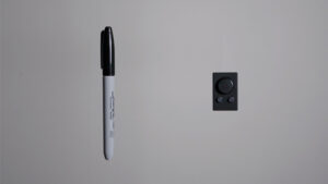 Close-up of a Sharpie marker attached to a wall with a hidden camera nearby.