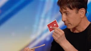 Up of Cyril performing a card trick with red playing cards.