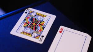 Close-up of a King of Spades and an empty card on a blue surface.
