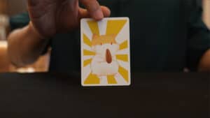 Close-up of a magician's hand holding a card with a cartoon hamster for magic tricks.