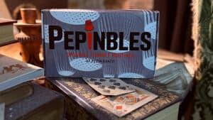 Close-up of Pepinbles thimble magic tricks with playing cards on a vintage table.