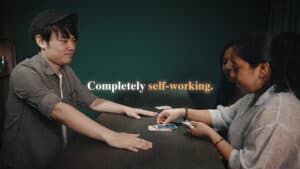 Two magicians performing a card trick with focused expressions at a table.