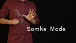 Magician demonstrating thumb tip magic trick with smoke for illusion.