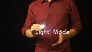 Performer demonstrating thumb tip magic trick with light illusion.