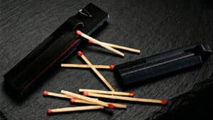 Matchstick magic trick with lit matches and a black case.