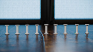 Close-up of a row of white magic trick spools on a wooden surface.