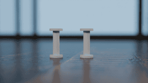 Close-up of two white MagReel spools on a wooden surface for magic tricks.