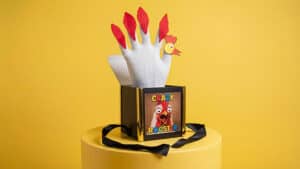 Colorful rooster puppet for magic tricks, created by Mr. Daba, on a yellow background.