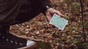 Person holding Orbit Forest playing cards outdoors in a forest setting.