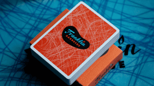 Franklin BBQ orange playing cards stacked on blue surface for magic tricks.