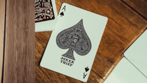 Elegant playing card featuring a detailed spade design with "Joker and the Thief" branding, set on a.
