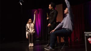 Magician performing a magic trick with touch chairs on stage.