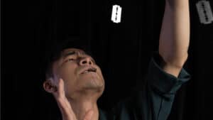 Performer executing a magical trick with hanging cards in a dark setting.