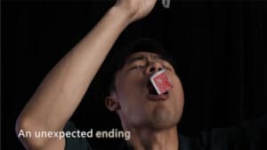 Performer balancing a playing card on his mouth during a magic trick performance.