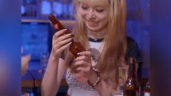 Young girl performing a tornado bottle magic trick with bottles in hand.