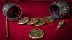 Traditional Tibetan prayer wheels with engraved symbols on a red cloth background.