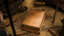 Close-up of a wooden magic trick card box on a rustic wooden surface.