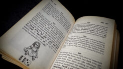Open book with magic instructions and a small illustrated clown figure, related to stage magic trick.
