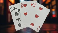 Close-up of three playing cards featuring hearts and clubs, used in magic tricks.