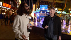 Vibrant image of two men enjoying Spectra by Luke Dancy at a lively carnival with colorful lights an.
