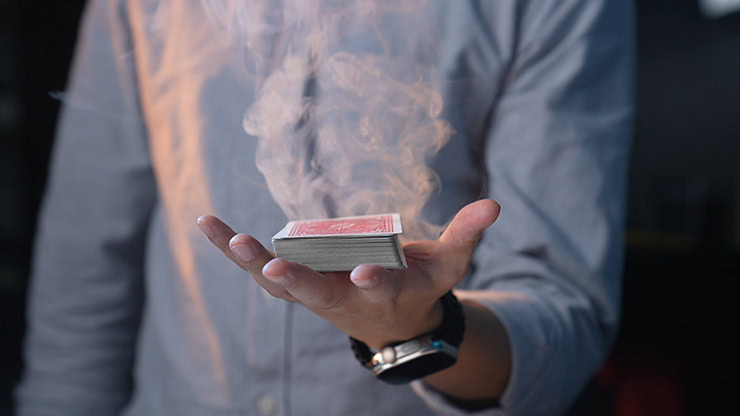 Performing Amor Watch magic trick with a deck of cards and smoke effect.