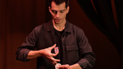 Magician performing the No Box magic trick with a playing card in hand.