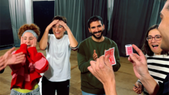 Performers demonstrate the No Box magic trick with cards in a lively setting.