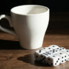 Large white ceramic cup with dice for magic tricks.