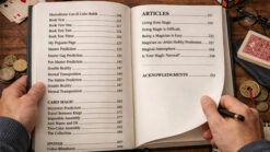 Magician performing a magic trick on stage with cards and coins.