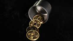 Silver coins spilling from a metal container, magic trick setup.