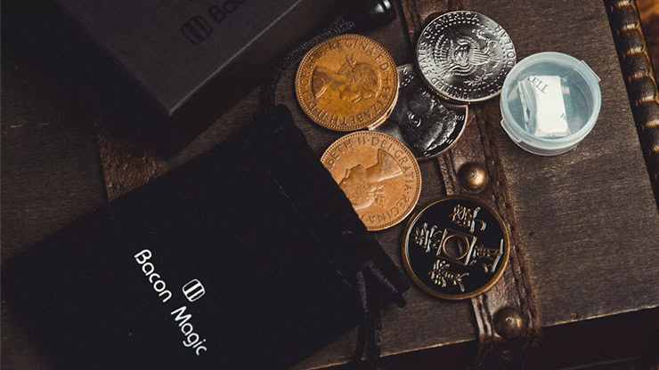 Close-up of a wing coin magic trick with coins and a small container on a wooden surface.