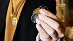 Close-up of a hand performing the Wing Coin illusion by Harry He & Bacon Magic.