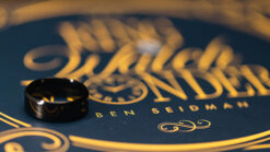 Close-up of a ring watch illusion with a black ring on a branded background.